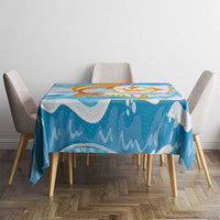 Blue dolphin tablecloth with orange and gold graphic, shown on a dining table with chairs.