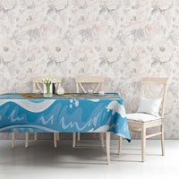 Blue tablecloth with orange and gold dolphin and wave pattern on a rectangular dining table.