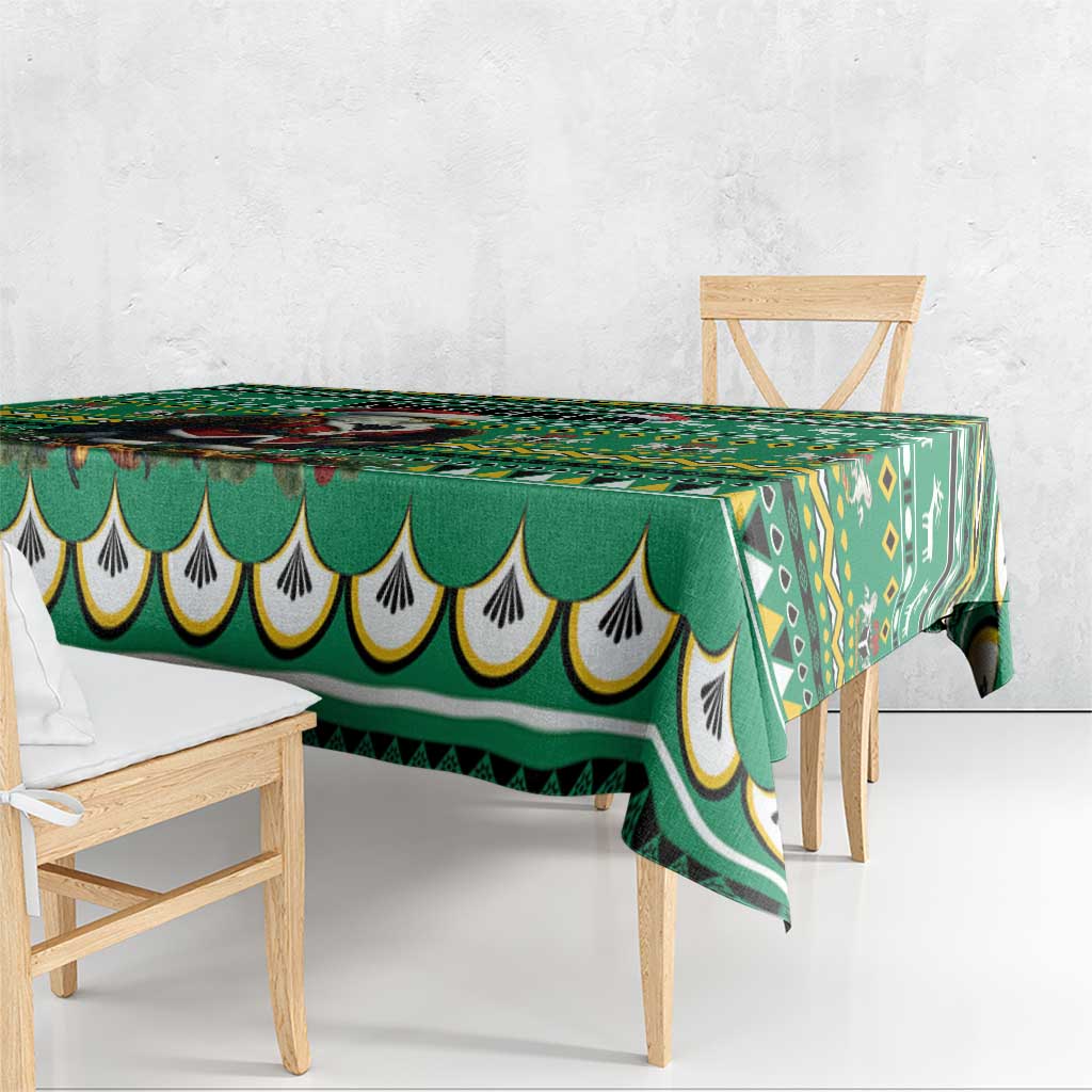 Green geometric tablecloth with scalloped edge draped over wooden dining table