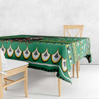 Green geometric tablecloth with scalloped edge draped over wooden dining table