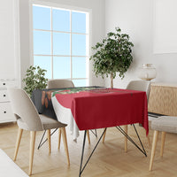 Red tablecloth with diagonal white stripe and black corner, featuring floral and crest print.