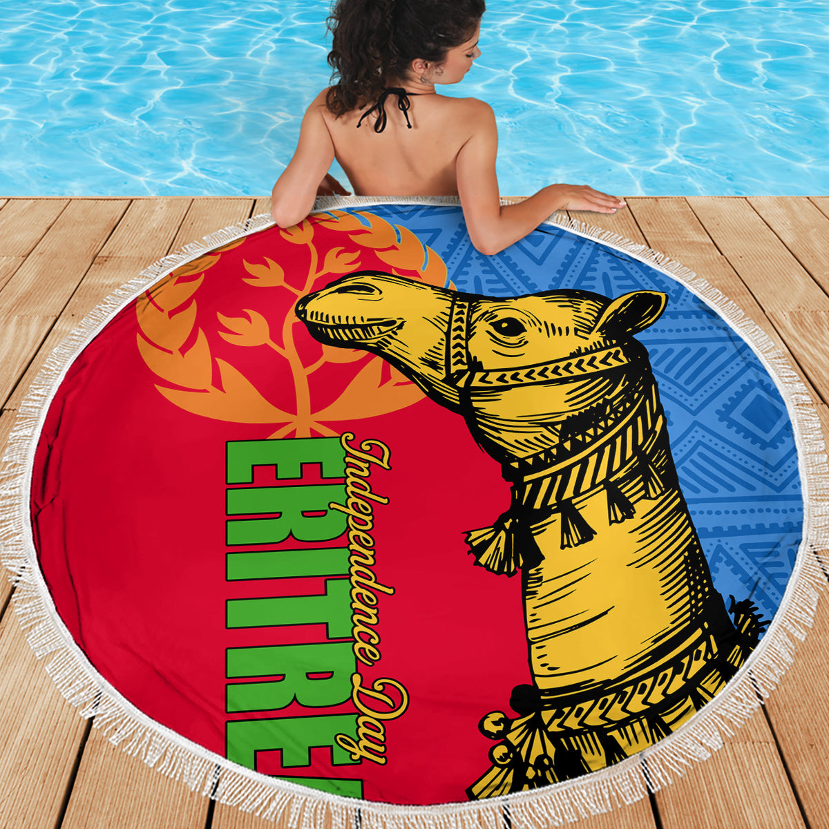 Round beach blanket with fringed edge, red and blue design featuring yellow camel on wooden deck