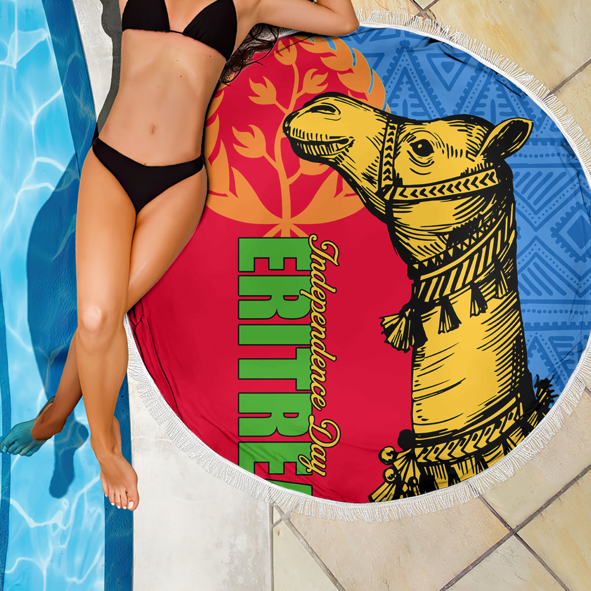 Round beach blanket with fringed edge, red and blue camel artwork draped near pool water