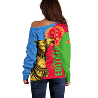 Women’s off-shoulder sweater back view with blue geometric panel and camel warrior graphic