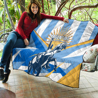 Blue and white Argentina quilt with yellow accents and warrior rider design, laid on patio