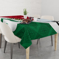 Green tablecloth with patterned center, red stripe, and black outline on dining table