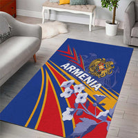 Blue area rug showing Armenia lettering, eagle crest, red and yellow rays, white figures.