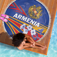 Round blue Armenia beach blanket with fringe trim, laid on woven mat