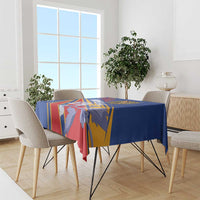 Blue tablecloth on dining table with colorful geometric and crest pattern across the top.