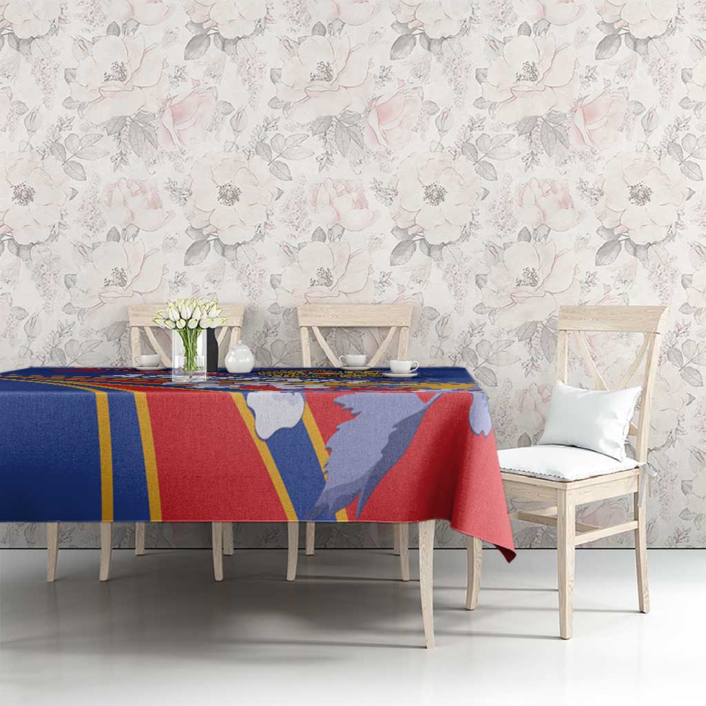 Blue tablecloth with red and yellow stripes and illustrated figures over dining table.