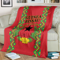Red blanket on couch with Guinea-Bissau Independence Day text, black star and laurel