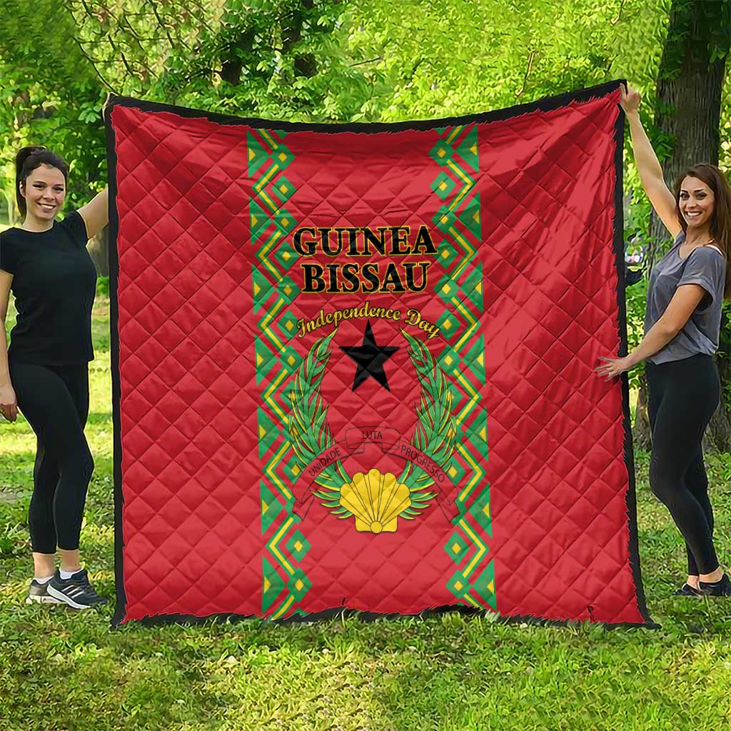 Red quilted blanket hanging outdoors with central Guinea-Bissau crest and green border