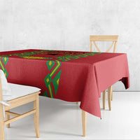 Red tablecloth with green diamond trim along the edge, draped over a dining table