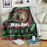 Black Christmas throw blanket on couch, Malawi pattern with gazelle, trees, and Malawi text