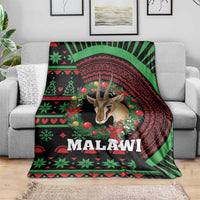 Black Christmas blanket on grey sofa, Malawi wreath design with gazelle and red-green accents