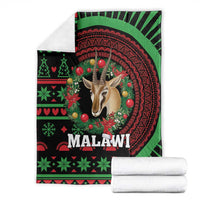 Folded black Malawi Christmas blanket with gazelle centerpiece and green-red holiday border