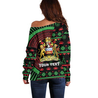 Black off-shoulder sweater with green/red crest graphic and bold 'YOUR TEXT' panel