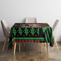 Christmas tablecloth on table with black base, green geometric and stripe pattern