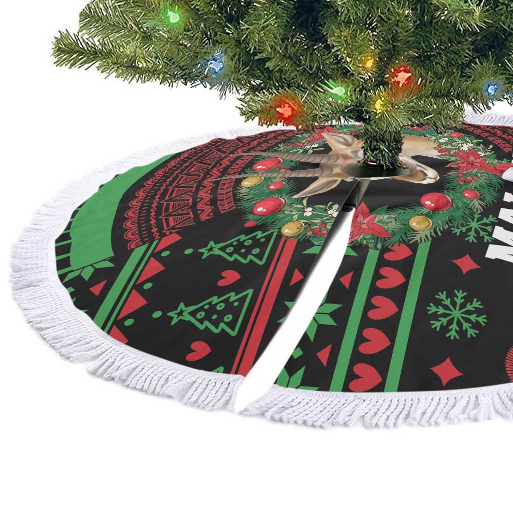 Round Christmas tree skirt with white fringe, green and red tribal deer pattern laid flat