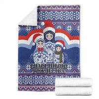 Blue Christmas blanket with Santa and matryoshka dolls, folded with matching white linens