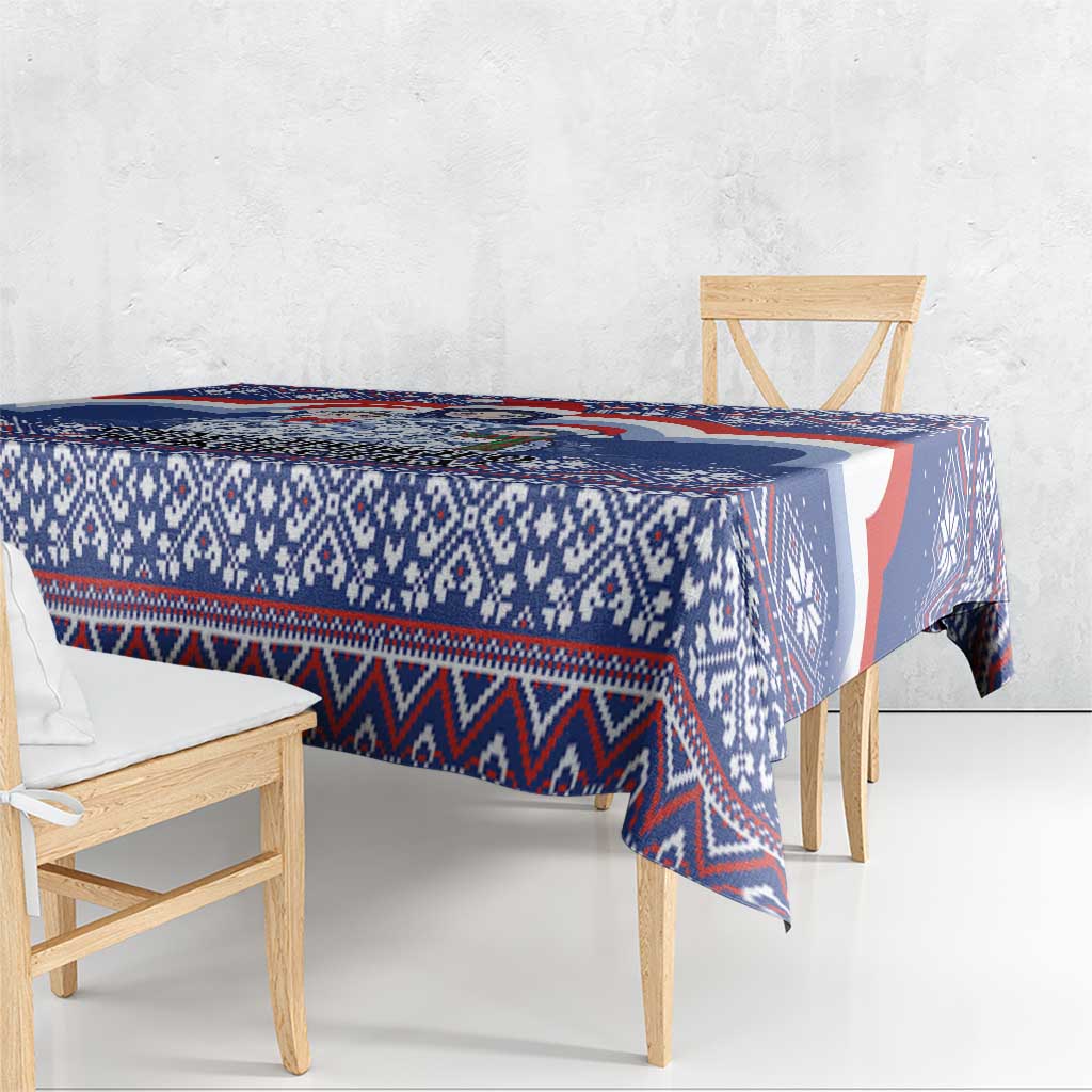 Blue and white patterned Christmas tablecloth draped over rectangular table.