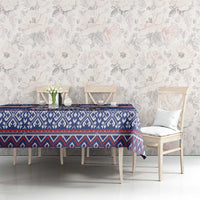 Blue patterned Christmas tablecloth on dining table with floral wall backdrop.