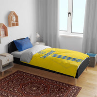 Yellow duvet with UKRAINE text and blue stripes, with two blue pillowcases