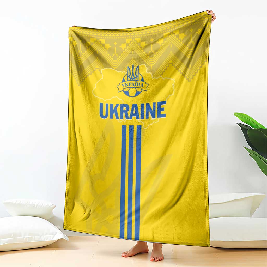 Yellow Ukraine blanket with large 'UKRAINE' logo and blue trident stripes, folk texture