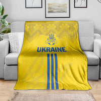 Yellow football blanket draped on sofa, blue 'UKRAINE' lettering and striped emblem