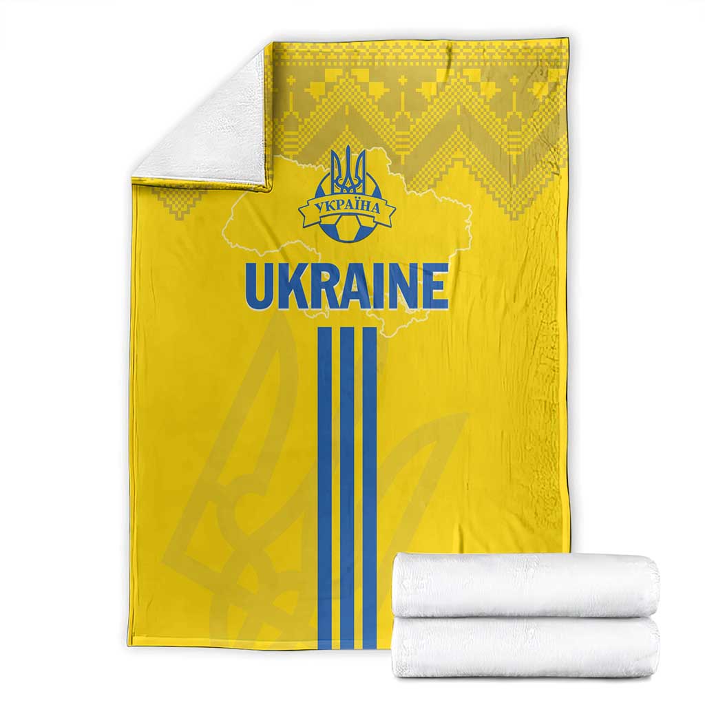 Yellow Ukraine football blanket with blue 'UKRAINE' emblem, backed by stacked towels