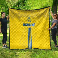 Yellow quilt with blue Ukraine emblem, text, and vertical stripes; unfolded on lawn