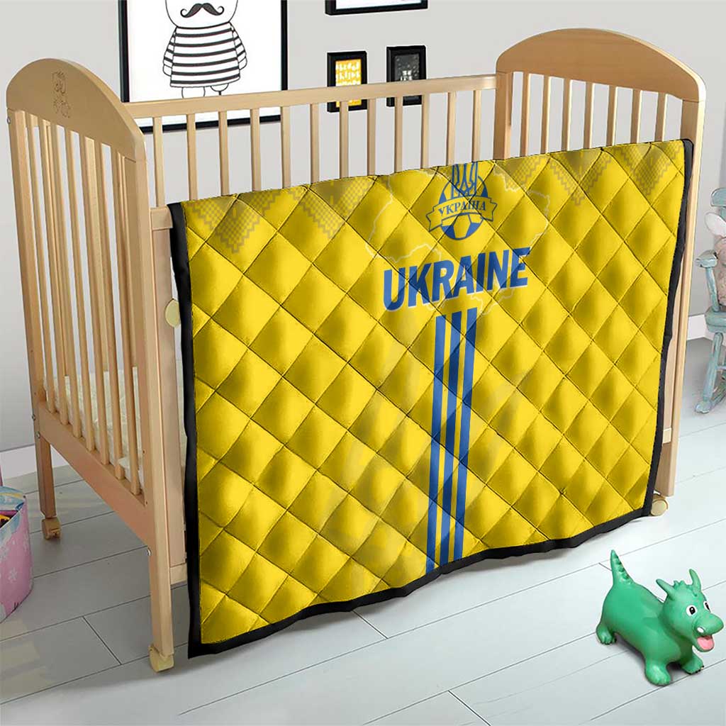 Yellow quilt in a wooden crib, showing blue Ukraine emblem, text, and vertical stripes
