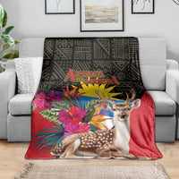 Antigua and Barbuda tropical deer print blanket on gray couch, red with deer and palm flowers
