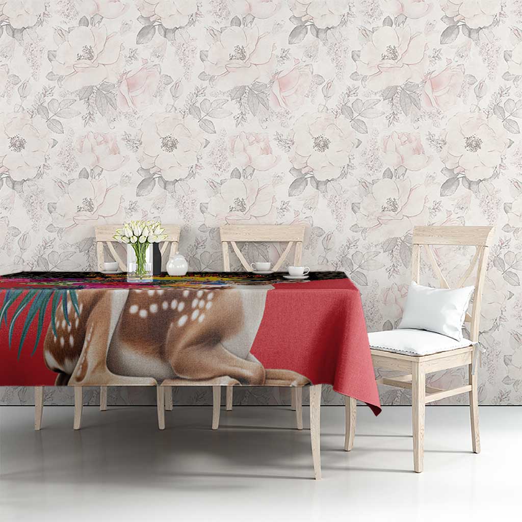 Red tablecloth with deer and floral pattern on dining table against pale wall