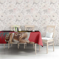 Red tablecloth with deer and floral pattern on dining table against pale wall