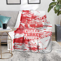 Red and white Turkey blanket with large TURKEY text, draped on gray couch.