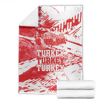 Red and white Turkey blanket with TURKEY text, with folded white bundles beside it.