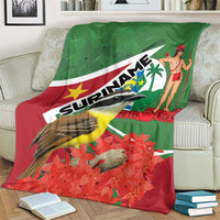Suriname-themed blanket on sofa, green top and red bottom with bird and floral leaves