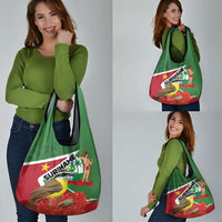 Green Suriname print tote bag on shoulder, bird and produce artwork on front