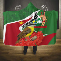Hooded blanket with green Suriname flag design, bird graphic, and small figure print