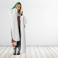 Sherpa-lined hooded blanket with green hood trim and white plush lining, worn by woman
