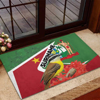 Green rubber doormat with Suriname bird-and-flower graphic, red-and-white corner border