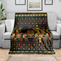 Kwanzaa throw blanket draped over sofa, black geometric pattern with kinara candle design