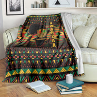 Kwanzaa blanket draped on couch, black with kinara candle graphic and geometric borders
