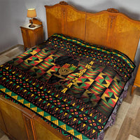 Kwanzaa festival quilt on bed with black base, colorful triangles, and kinara candle emblem