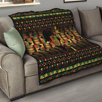 Kwanzaa festival quilt folded on sofa with black, red, green geometric design and kinara