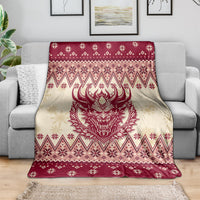 Red and cream Krampus-themed Christmas blanket draped over a couch with Nordic motifs