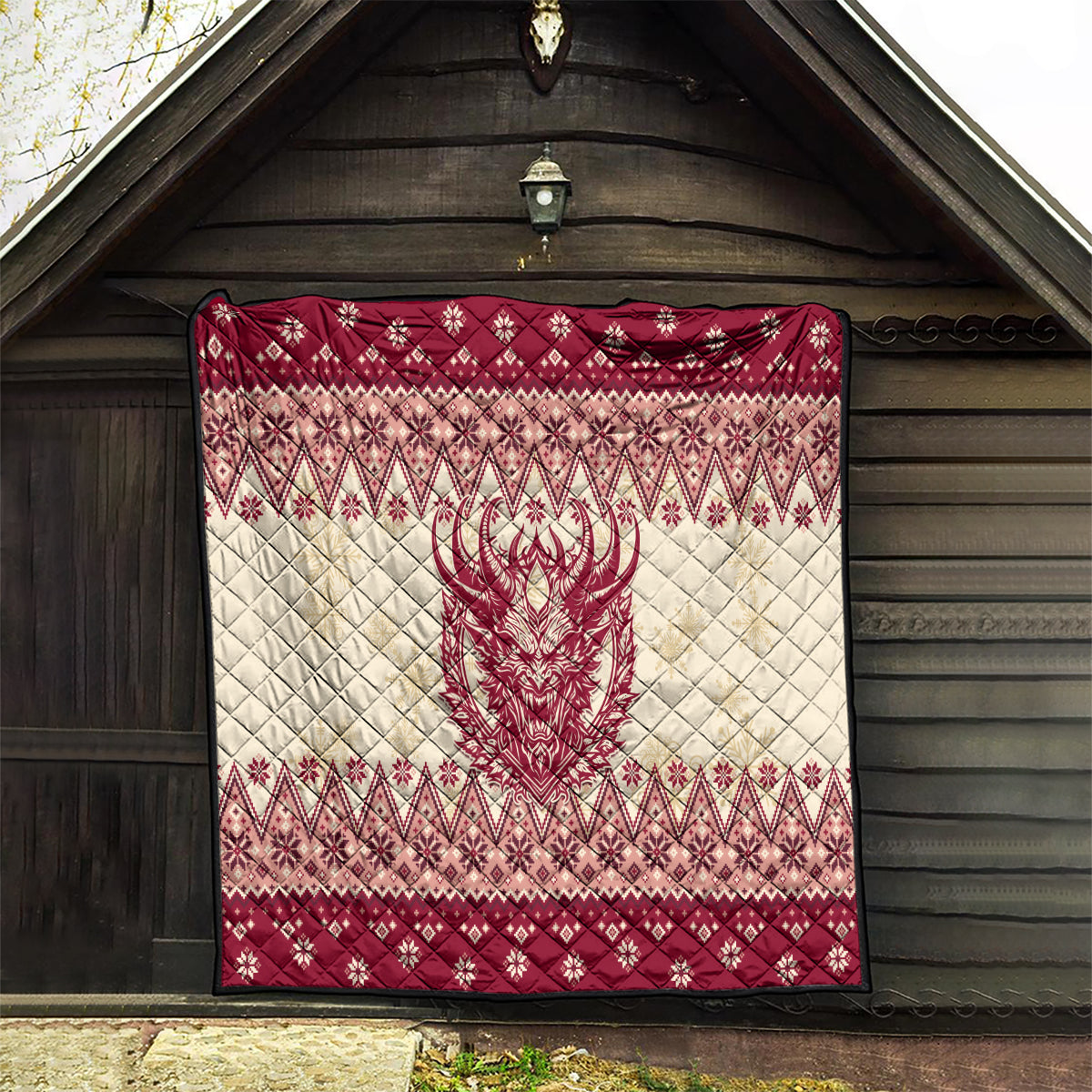 Red and cream quilt hung outdoors with Krampus face centerpiece and diamond Nordic trim.