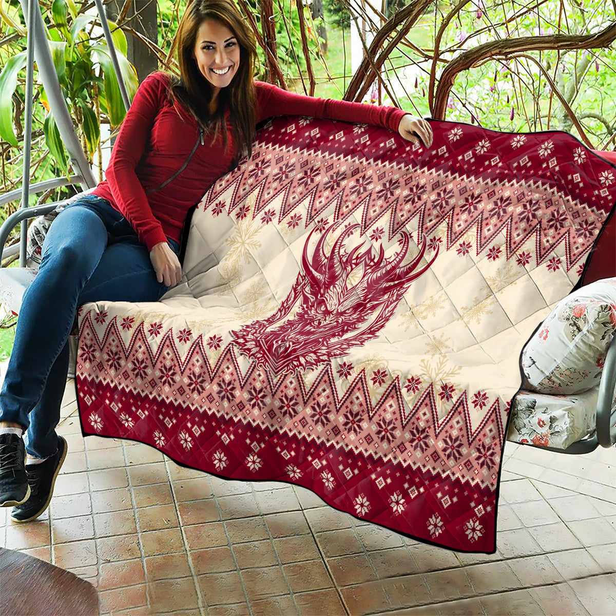 Red and cream quilt held on sofa, featuring Krampus face and geometric diamond holiday print.