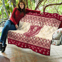Red and cream quilt held on sofa, featuring Krampus face and geometric diamond holiday print.